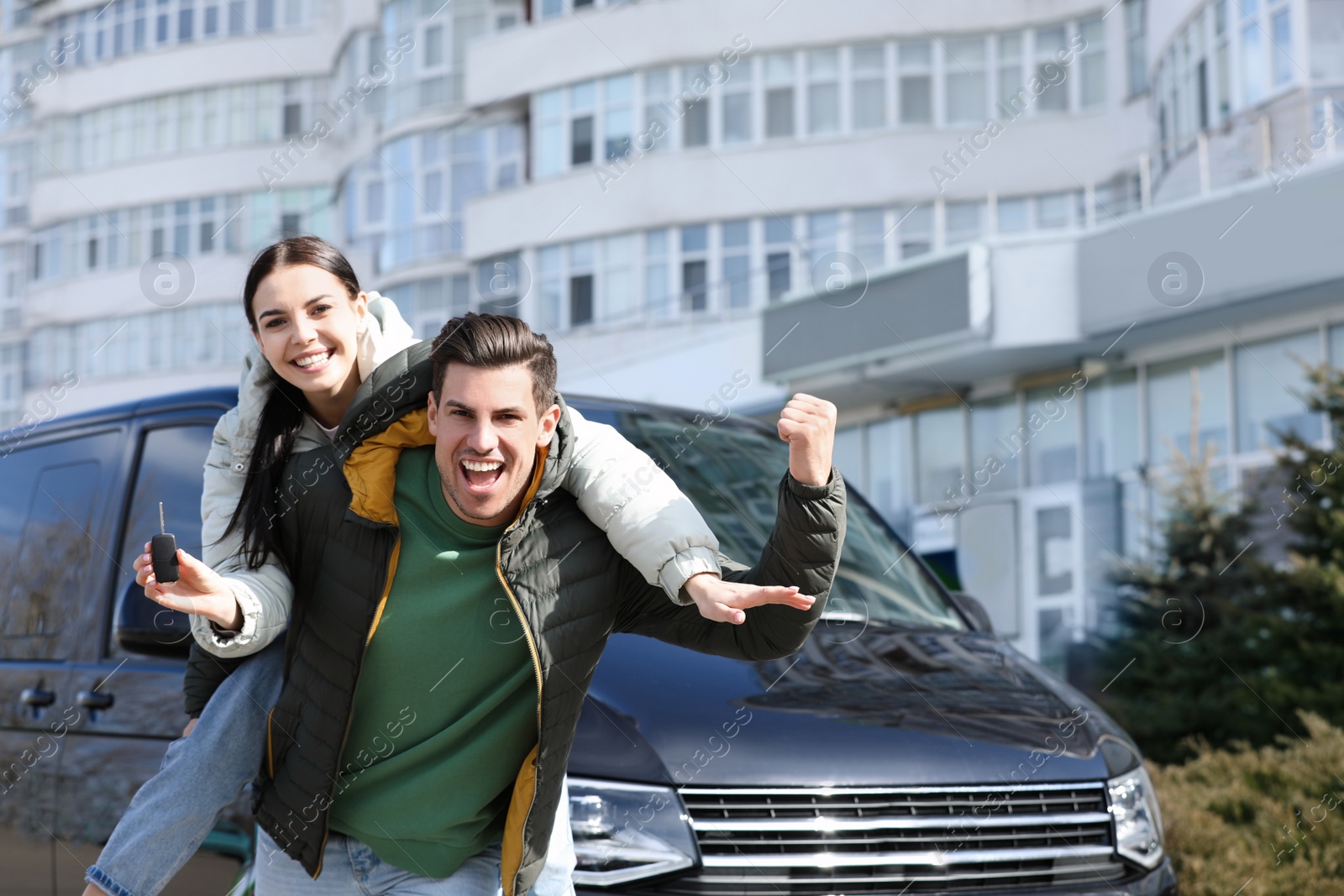 Photo of Happy couple with key near car on city street. Buying new auto