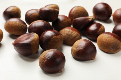 Sweet fresh edible chestnuts on white table, closeup