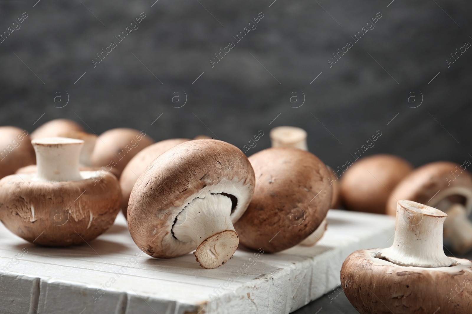 Photo of Fresh champignon mushrooms on wooden cutting board, closeup