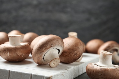 Fresh champignon mushrooms on wooden cutting board, closeup