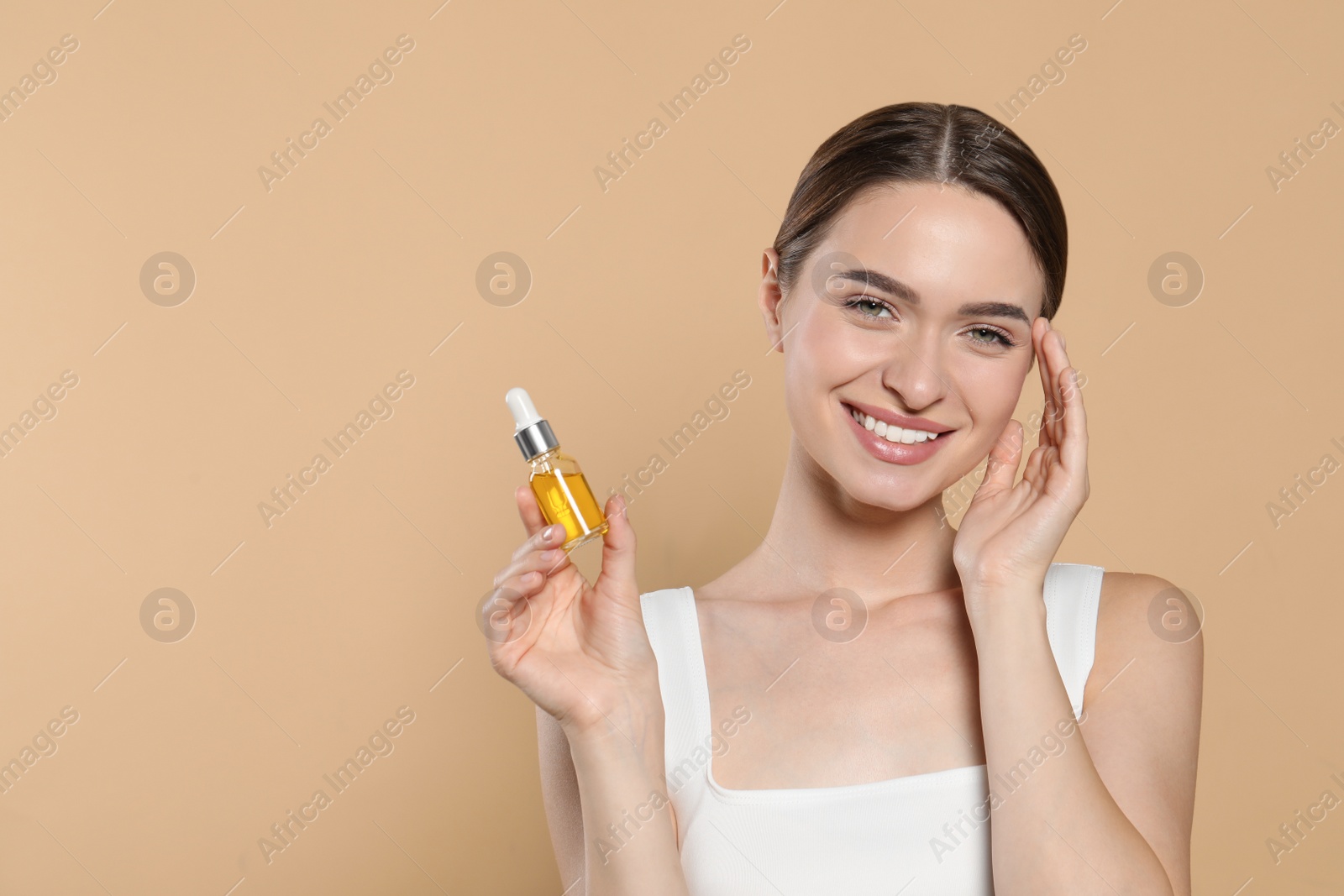 Photo of Young woman with bottle of essential oil on beige background, space for text