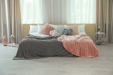 Photo of Comfortable bed with pillows and plaid in modern room interior