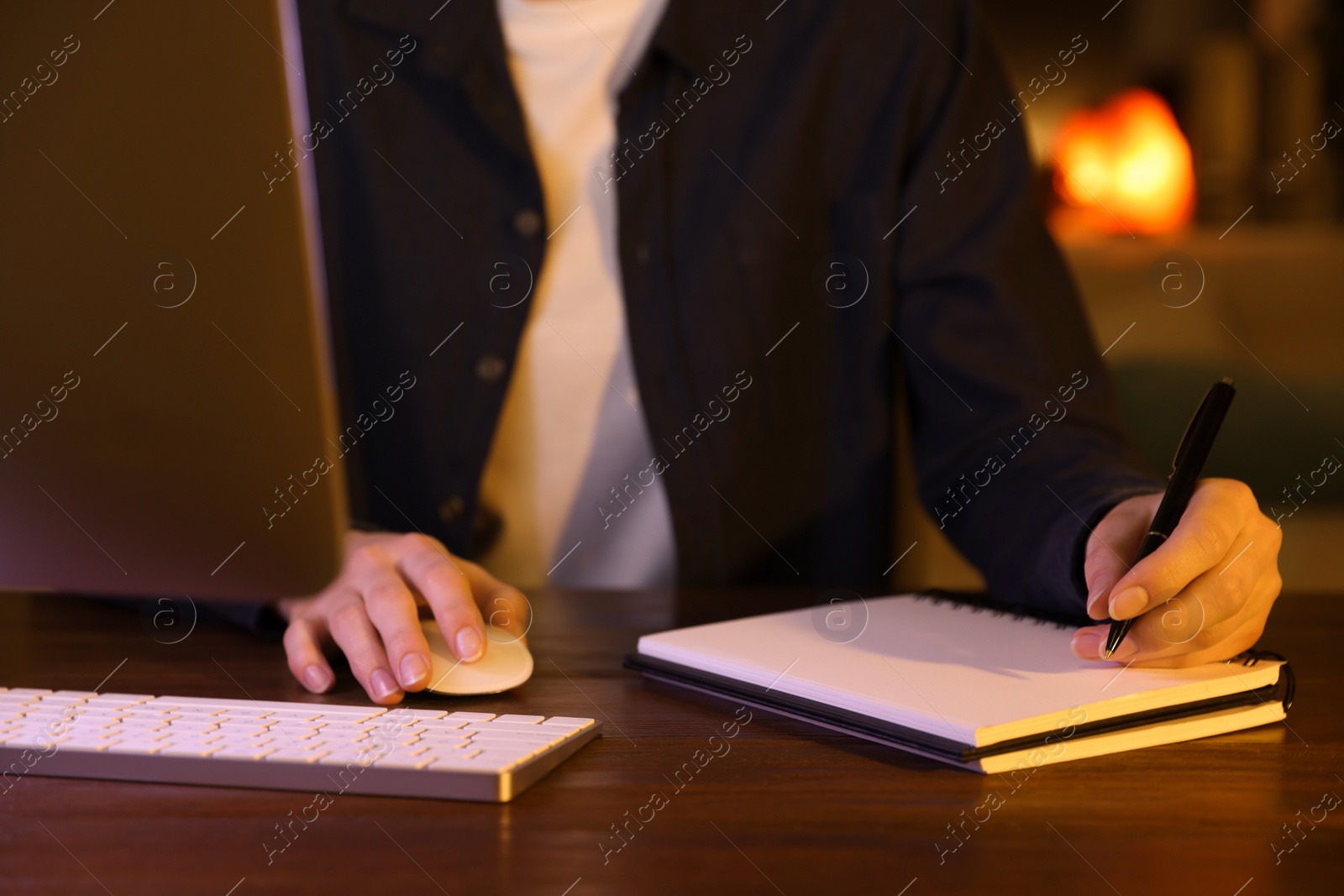 Photo of Home workplace. Woman working on computer at wooden desk indoors, closeup