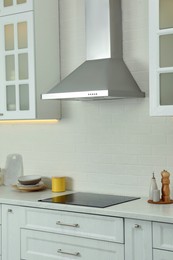 Photo of Elegant kitchen interior with modern range hood over cooktop and stylish furniture