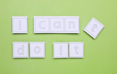 Photo of Motivation concept. Changing phrase from I Can't Do It into I Can Do It by removing paper with letter T on light green background, flat lay