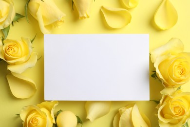 Beautiful roses, petals and blank card on yellow background, flat lay. Space for text