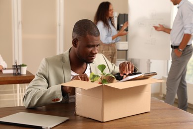 New coworker unpacking box with personal items at workplace in office