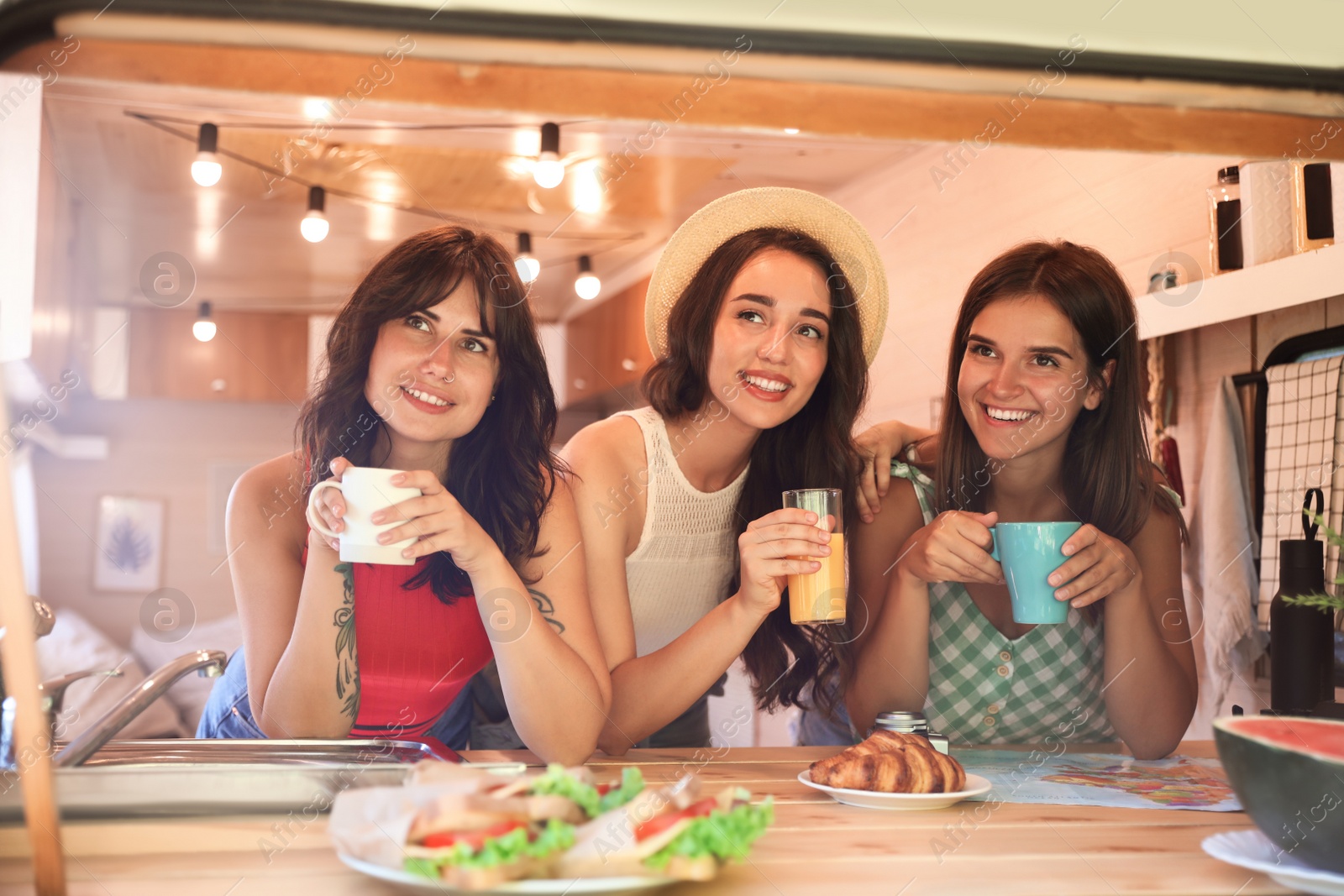 Photo of Happy young women having breakfast in trailer. Camping vacation