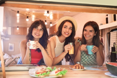 Photo of Happy young women having breakfast in trailer. Camping vacation