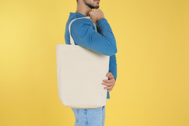 Young man holding textile bag on color background, closeup. Mockup for design