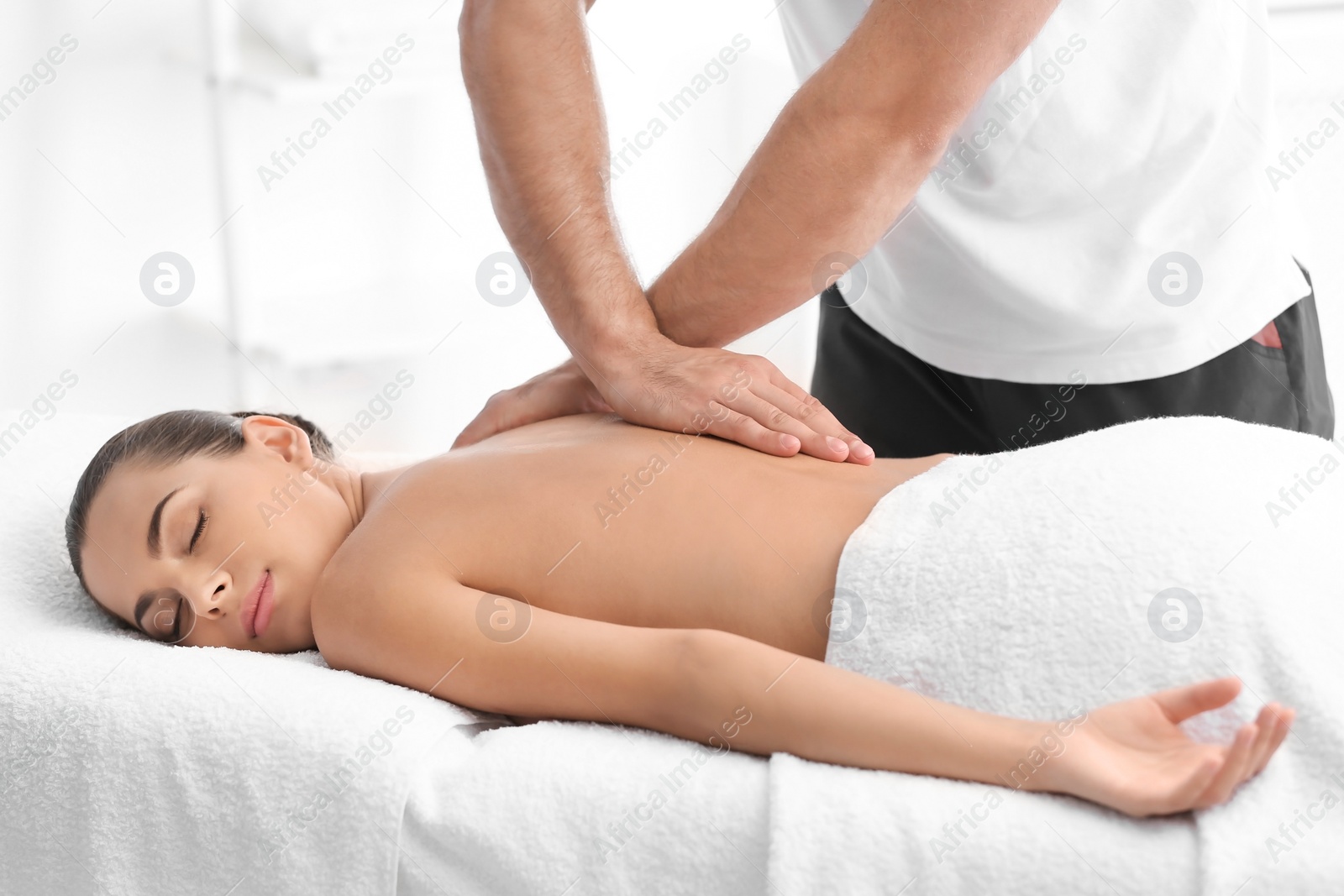 Photo of Relaxed woman receiving back massage in wellness center