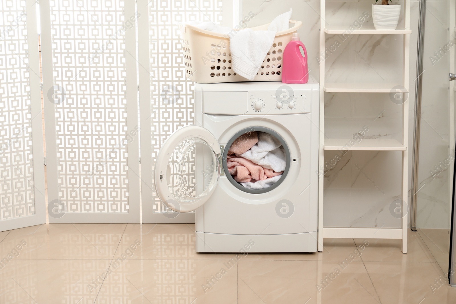 Photo of Modern washing machine with towels in bathroom