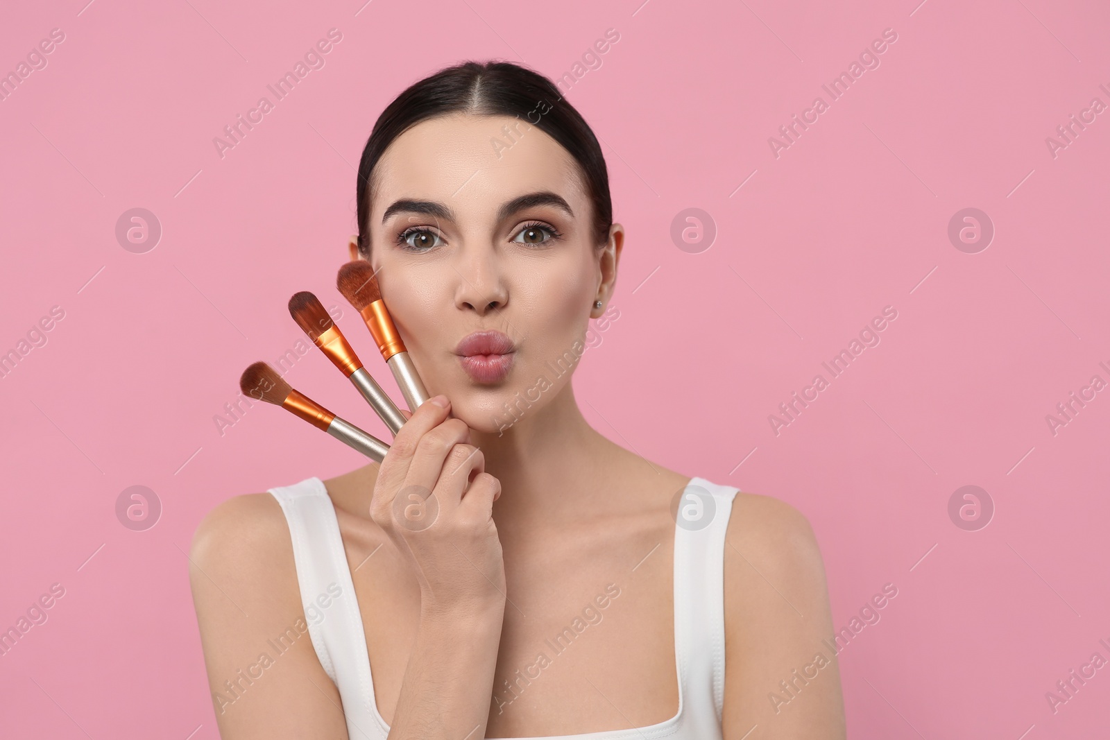 Photo of Beautiful woman with different makeup brushes on pink background. Space for text