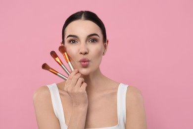 Beautiful woman with different makeup brushes on pink background. Space for text