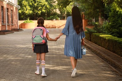 Photo of Mother taking her daughter to school, back view