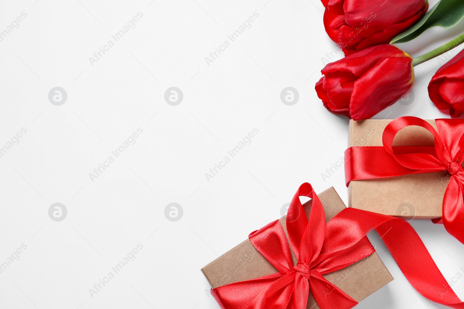 Photo of Beautiful gift boxes and red tulip flowers on white background, flat lay. Space for text