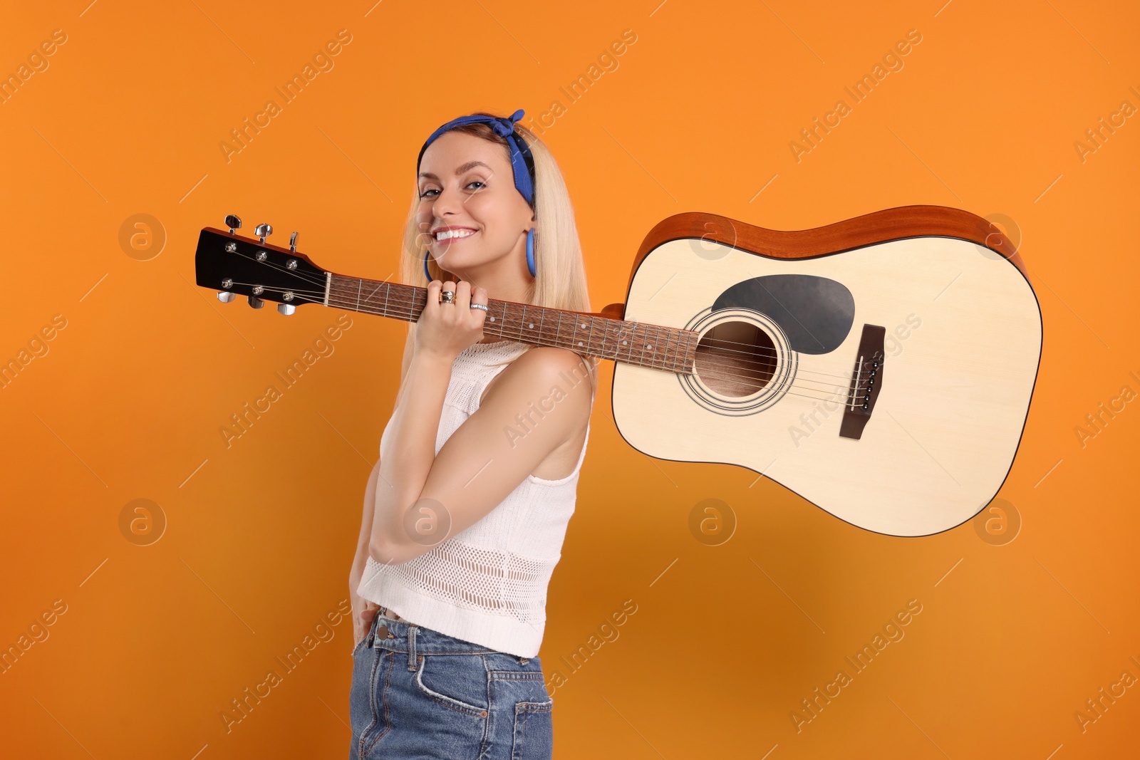 Photo of Happy hippie woman with guitar on orange background