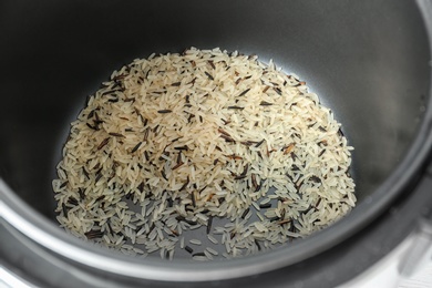 Photo of Modern multi cooker with raw rice, closeup