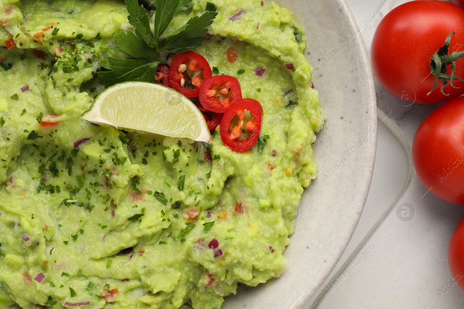 Photo of Delicious guacamole and ingredients on white table, flat lay