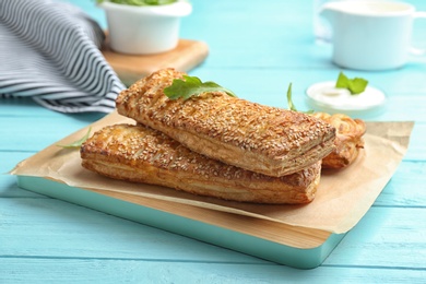 Photo of Fresh delicious puff pastry served on light blue wooden table