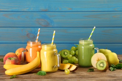 Photo of Mason jars of different tasty smoothies and fresh ingredients on wooden table