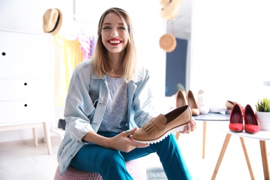 Portrait of female fashion blogger with shoe at home
