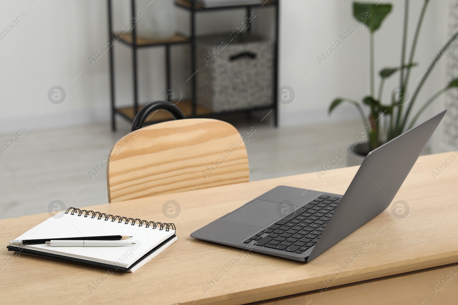 Photo of Home workspace. Laptop and stationery on wooden desk in room. Space for text