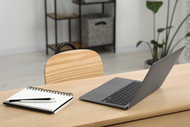 Photo of Home workspace. Laptop and stationery on wooden desk in room. Space for text