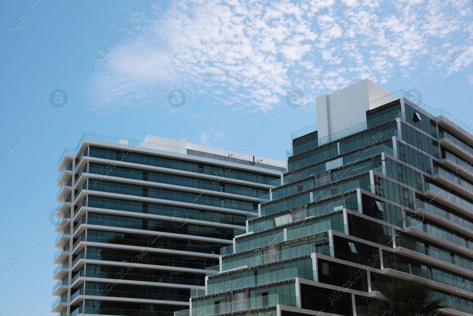 Photo of Exterior of residential building with balconies against blue sky, low angle view