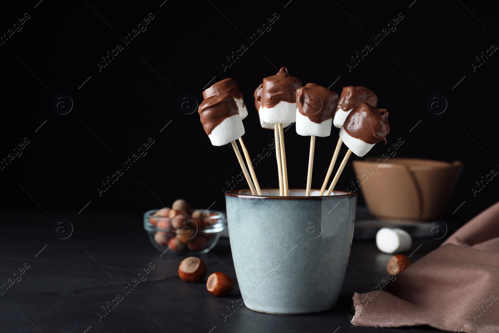 Photo of Delicious marshmallows covered with chocolate on black table