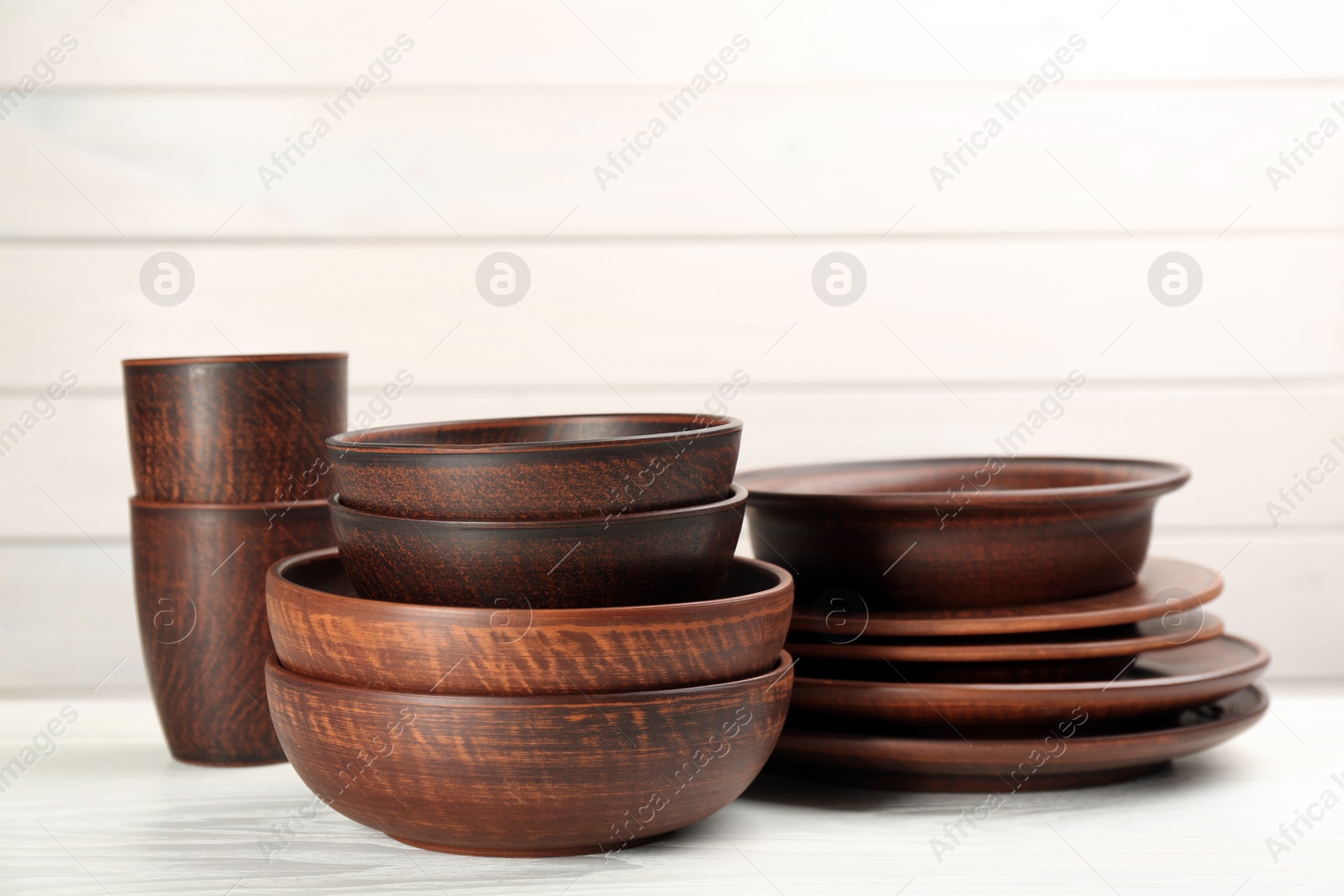 Photo of Set of clay utensils on white wooden table