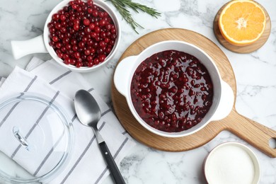 Photo of Fresh cranberry sauce in bowl served on white marble table, flat lay