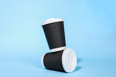 Photo of Paper cups with white lids on light blue background. Coffee to go