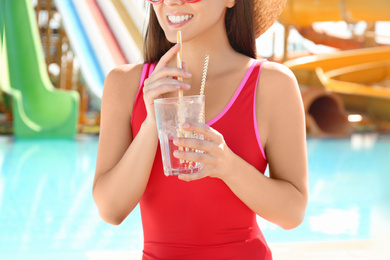 Woman with glass of refreshing drink in water park, closeup