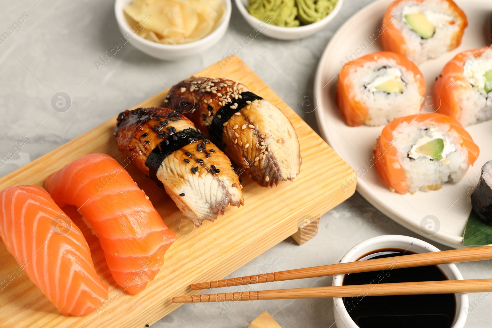 Photo of Delicious sushi rolls on light grey marble table