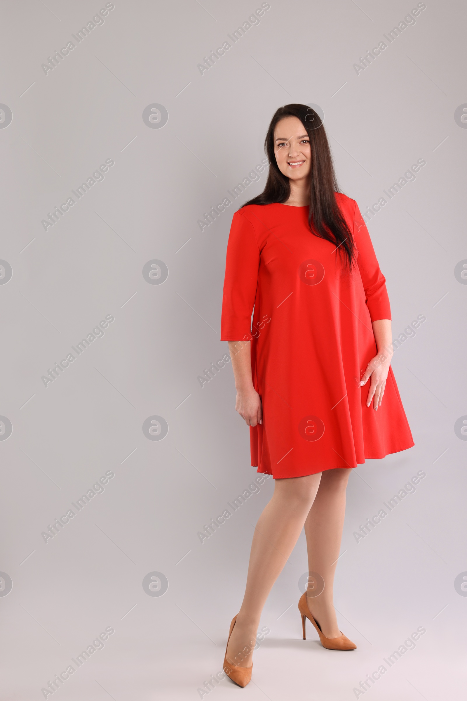 Photo of Beautiful overweight woman in red dress on light grey background