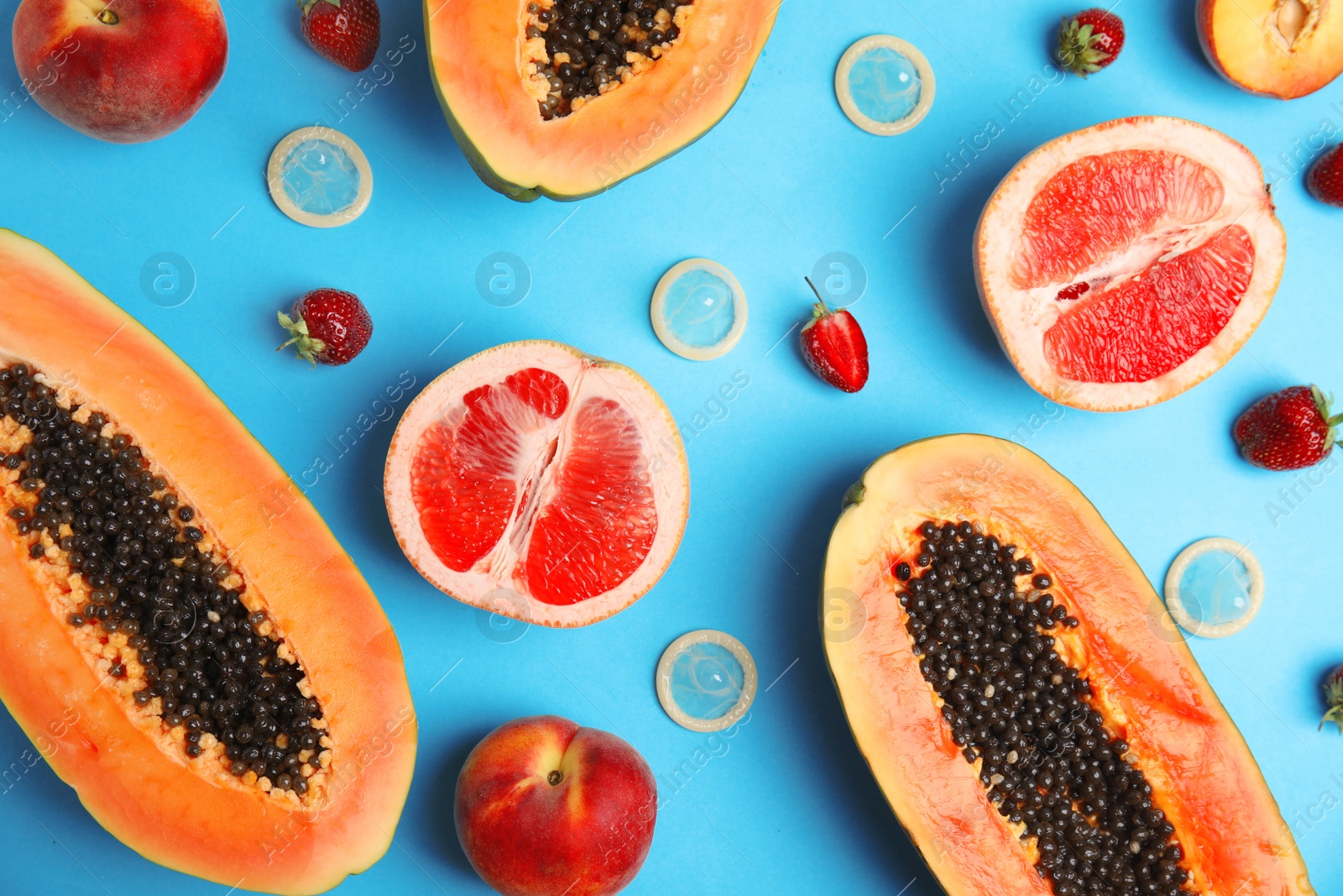 Photo of Flat lay composition with condoms and exotic fruits on blue background. Erotic concept