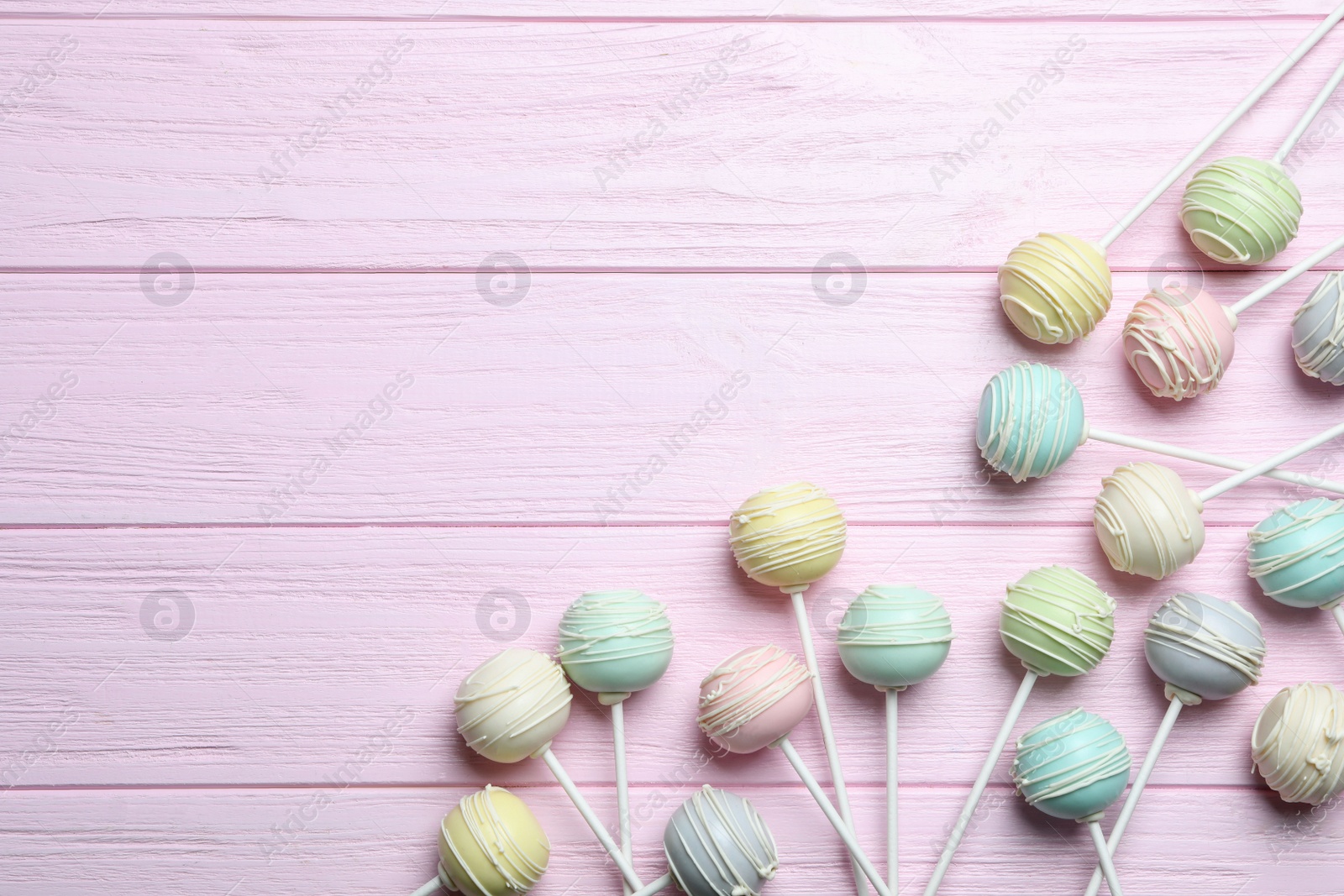 Photo of Sweet cake pops on pink wooden background, flat lay. Space for text