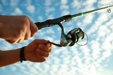 Photo of Fisherman with rod fishing under blue sky, closeup