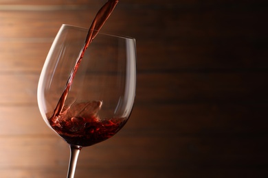 Pouring red wine into glass on blurred background. Space for text