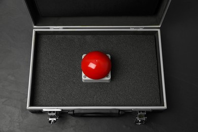 Photo of Red button of nuclear weapon in suitcase on black background, above view. War concept