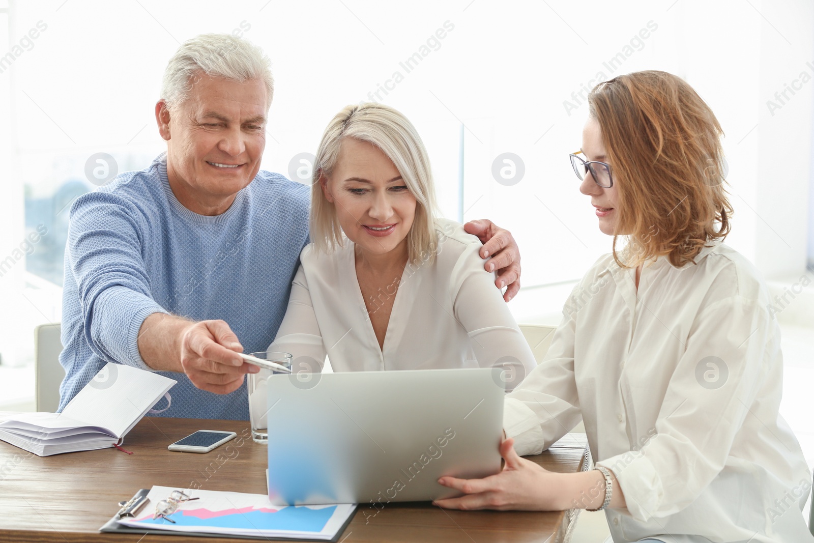 Photo of Female manager consulting mature couple in office