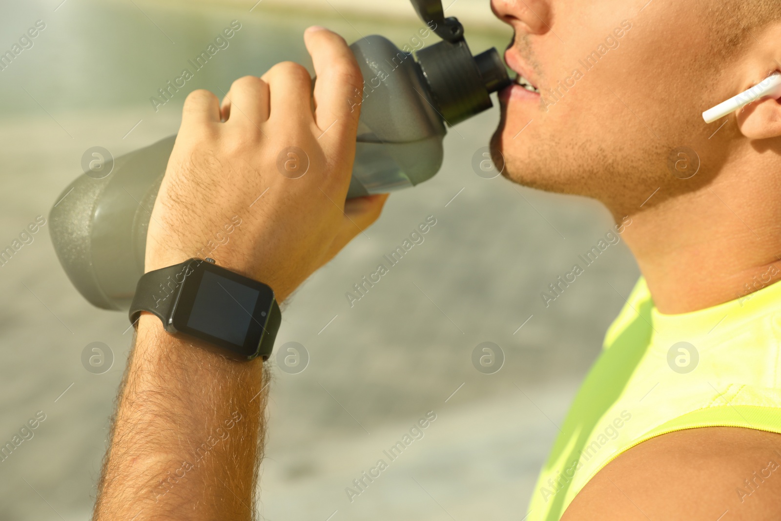 Photo of Man with modern smart watch drinking water outdoors, closeup