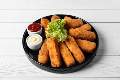 Photo of Plate of cheese sticks and sauces on table