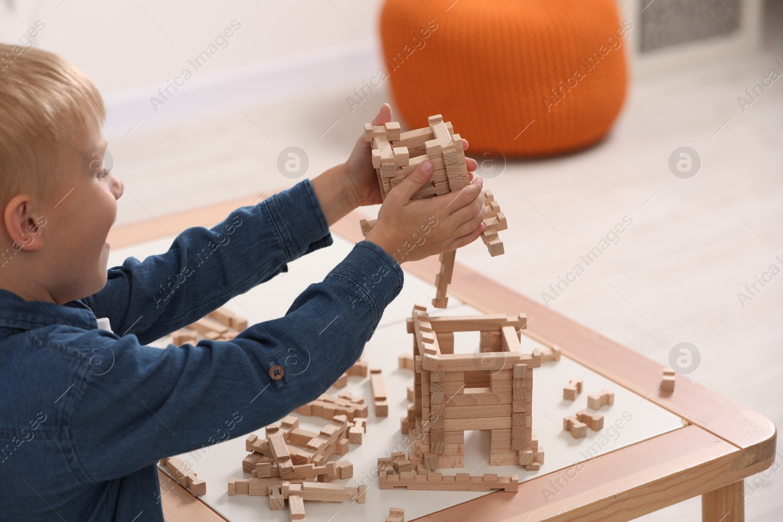 Photo of Little boy playing with wooden tower at table indoors, closeup. Child's toy