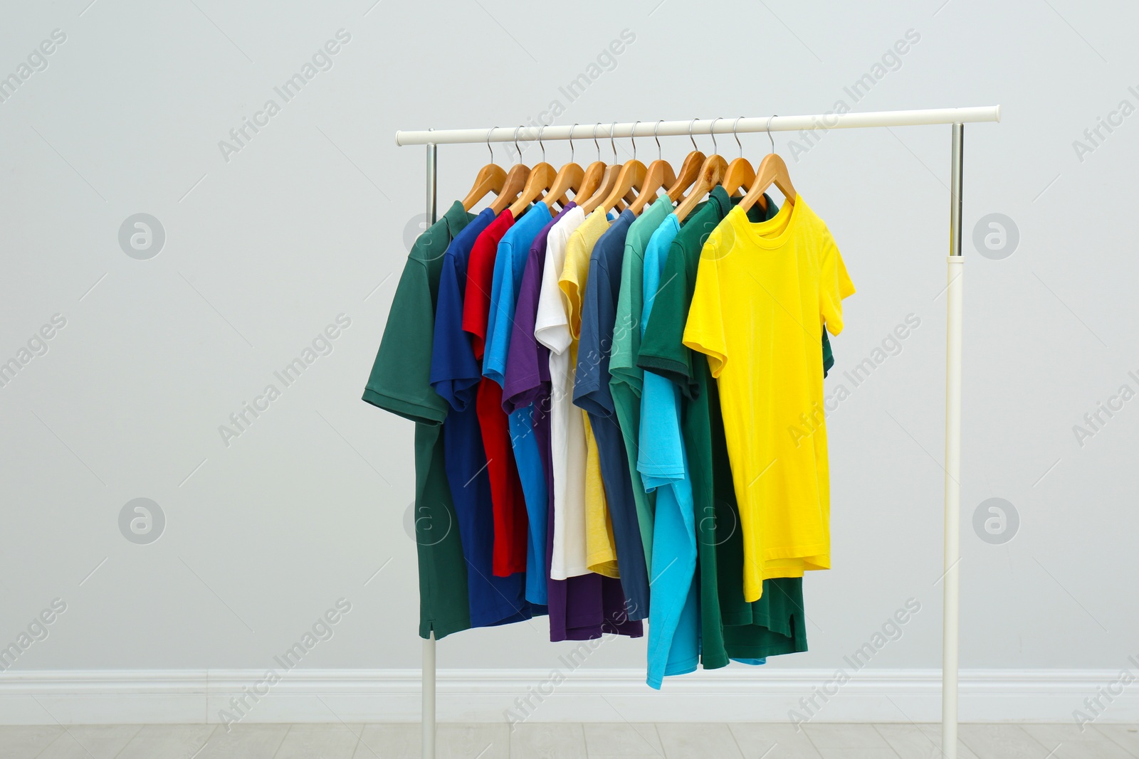 Photo of Rack with stylish colorful t-shirts in room