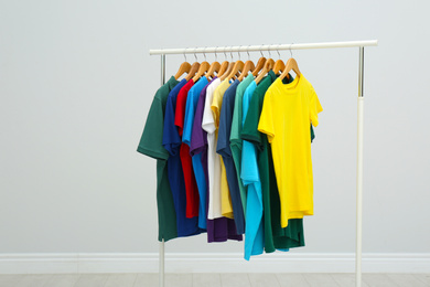 Photo of Rack with stylish colorful t-shirts in room