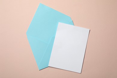 Letter envelope and card on beige background, top view. Space for text