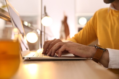 Man working with laptop at table in cafe, closeup