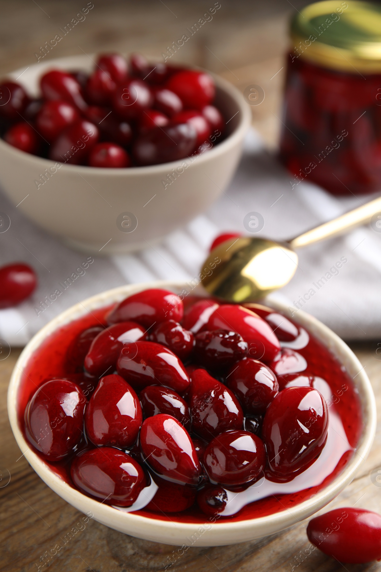 Photo of Delicious dogwood jam with berries in bowl on wooden table, closeup. Space for text